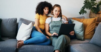 Tablet, Love And Lesbian Couple Relaxing On A Sofa In The Living Room Networking On Social Media.
